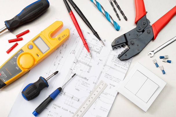 Various electrician tools and components including a multimeter, screwdrivers, wirecutters , drill bits, switches and sockets. - Photo, Image