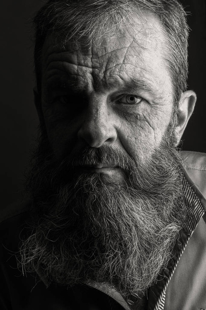 Black and white portrait picture of a senior man with a full beard. Close up head shot with close up of face. Grumpy serious facial expression. - Photo, Image