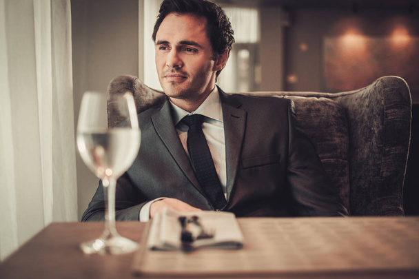 Un jeune homme confiant assis au restaurant qui attend quelqu'un
 - Photo, image