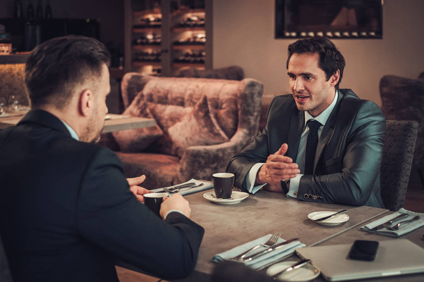 Two confident business men have business lunch at restaurant - Photo, Image