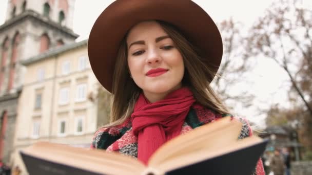 Joven chica hermosa en sombrero libro de lectura en el parque de la ciudad. Movimiento lento
. - Metraje, vídeo