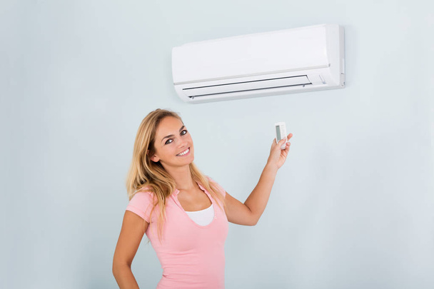 Woman Operating Air Conditioner - Fotó, kép