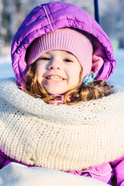 Cute girl sitting in the sled in winter park. - Zdjęcie, obraz