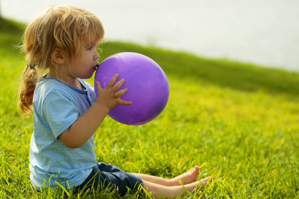 Cute baby boy with violet toy balloon - Foto, afbeelding