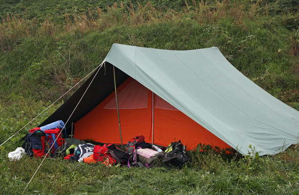 Oranje en groen tent met veel rugzakken - Foto, afbeelding