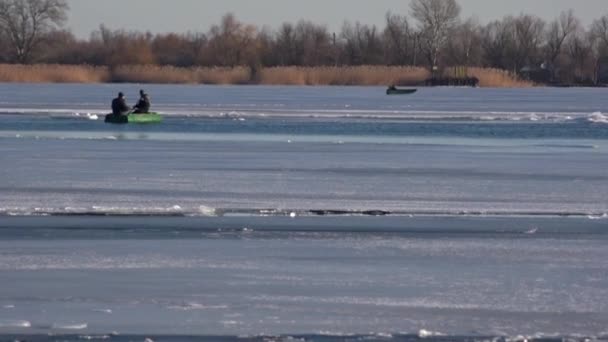 Vervoer voor verkeer op het ijs. Winter, twee mannen in een boot. Overstekende kinderen in de winter op de rivier. - Video