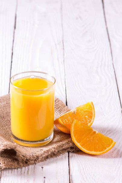 lasillinen mehua ja appelsiininviipaleita pöydällä
 - Valokuva, kuva