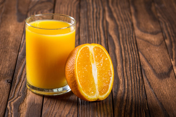 El vaso del jugo y los trozos de naranja sobre la mesa
 - Foto, Imagen