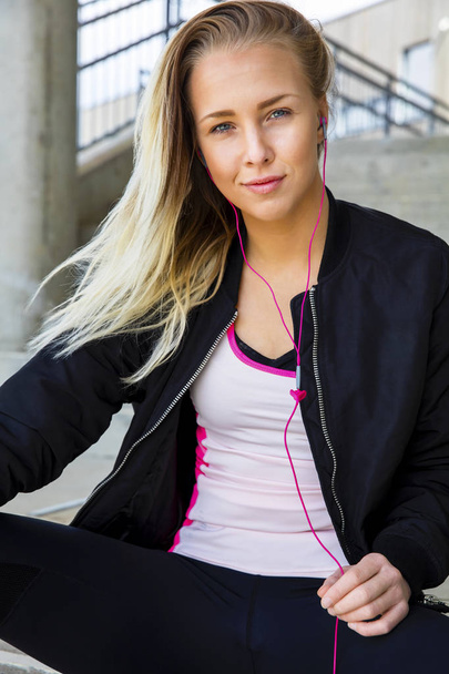Blondi nainen urheiluvaatteet kuuntelee musiikkia kuulokkeiden kautta
 - Valokuva, kuva