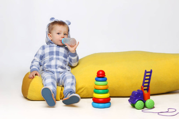  Дитячий хлопчик грає з іграшками і п'є з чашки сиппі
. - Фото, зображення