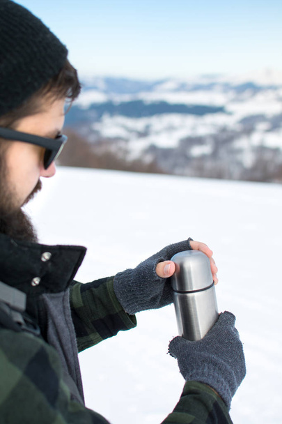 Man using  thermos in on a snowy mountain - Photo, Image