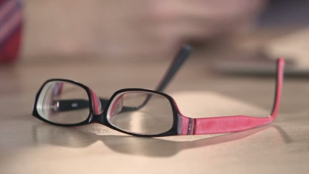 Closeup of eyeglasses on table, nice accessories for person with bad eyesight - Materiaali, video