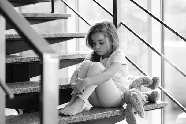 Sad little girl sitting on stairs - Photo, Image