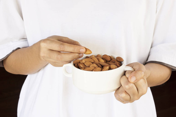 Almonds on a white background, or on a plain wooden table. Almonds in women's hands. - Foto, Bild