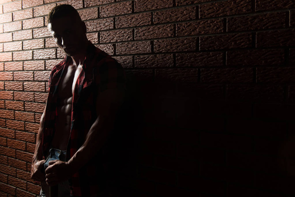 Bodybuilder Flexing Muscles On Wall of Bricks - Фото, изображение