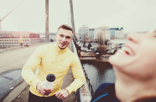 Couple athletes talking after a workout on city bridge - Foto, immagini