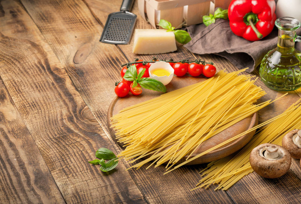 Spaghetti with ingredients for cooking pasta on round wooden boa - Fotografie, Obrázek