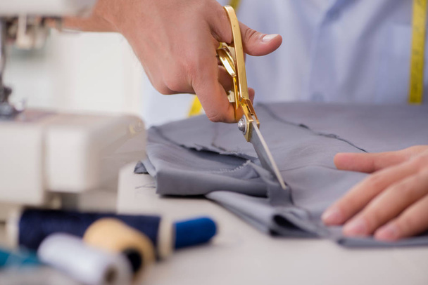 Young man tailor working on new clothing - 写真・画像