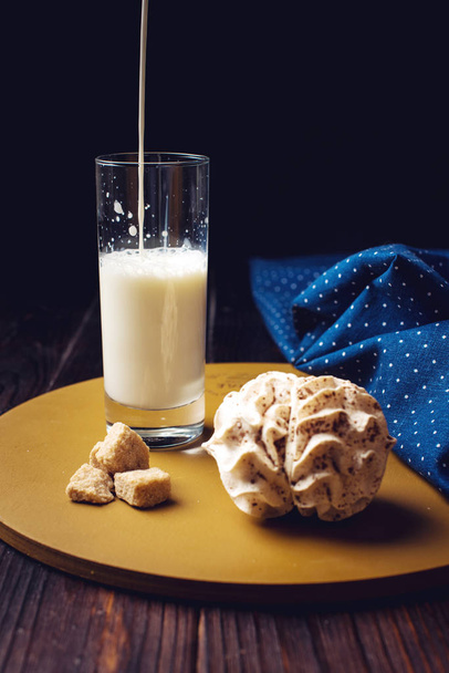melk gieten in een glas op houten tafel - Foto, afbeelding