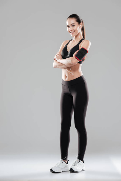 Full length of smiling confident sportswoman standing with arms crossed - Фото, зображення