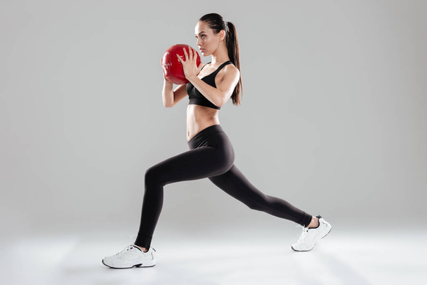 Focused beautiful young sportswoman doing exercises with medicine ball - Foto, Imagen