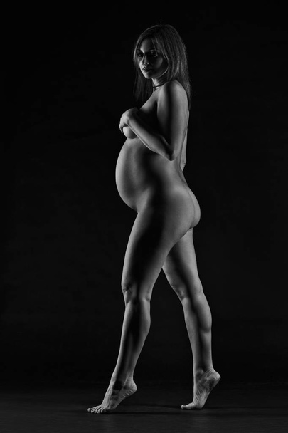Beautiful naked pregnant woman on black studio background, pregnancy nude concept - Photo, Image