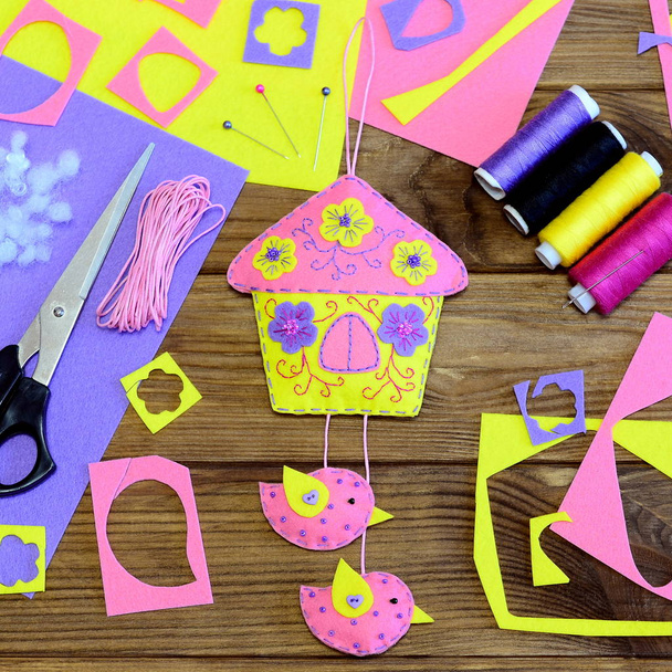 Spring felt toy house decoration crafts, scissors, thread kit, colored felt sheets, needle, ribbon on a wooden background. Handmade Mothers day or Easter craft diy for kids flatlay. Crafting sewing table top view. Embroidery idea - Photo, Image