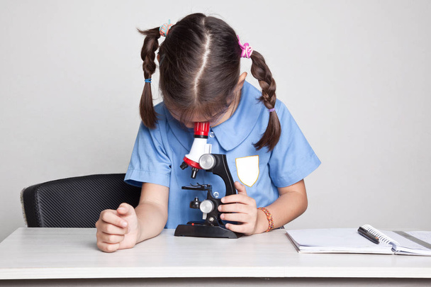 uczennica, siedząc z mikroskopem - Zdjęcie, obraz