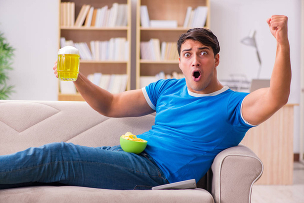 Man watching football at home sitting in couch - Foto, Bild