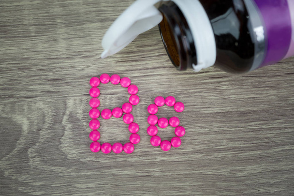 ピンク錠剤成形形状ウッドの背景に B6 アルファベットに - 写真・画像