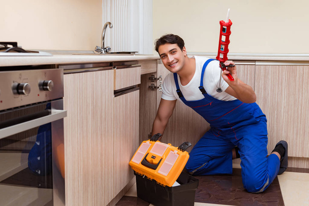 Молодой ремонтник, работающий на кухне - Фото, изображение