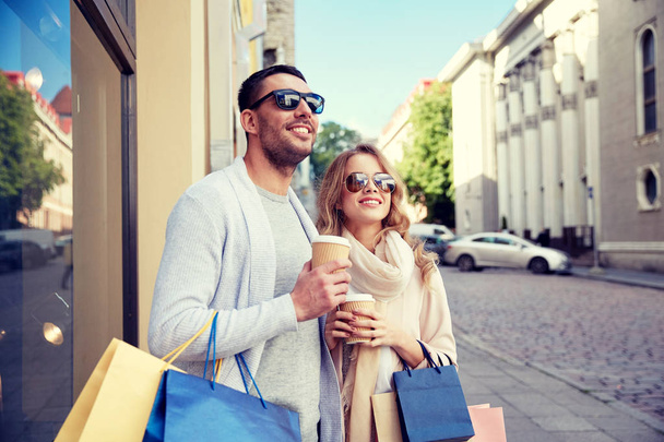 happy couple with shopping bags and coffee in city - Foto, imagen