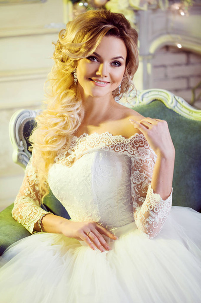 Portrait of charming woman in wedding dress. The girl bride sits in a chair - Фото, изображение