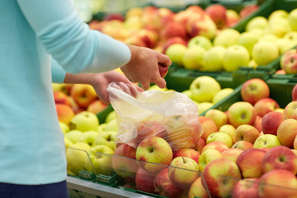 woman with bag buying apples at grocery store - Foto, immagini