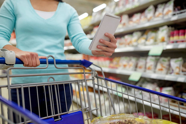 woman with food in shopping cart at supermarket - Φωτογραφία, εικόνα