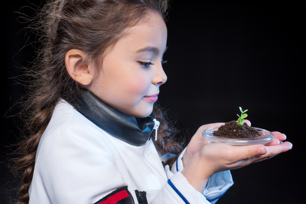 Girl astronaut holding plant - Φωτογραφία, εικόνα