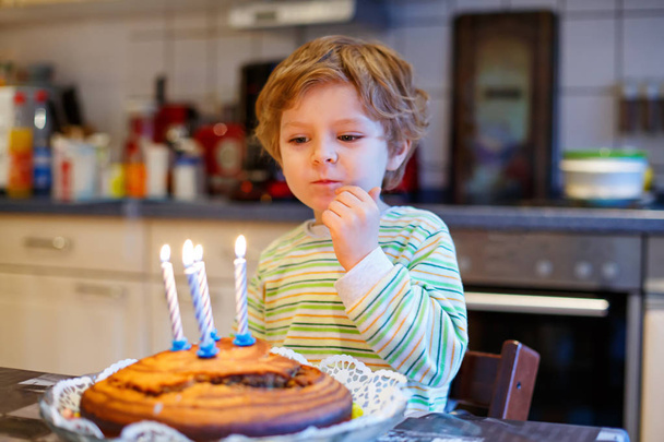 Kleiner Junge feiert Geburtstag und bläst Kerzen auf Kuchen - Foto, Bild