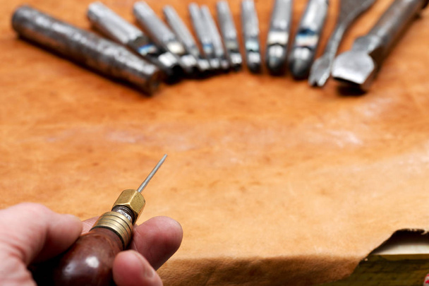 Werkzeuge aus Leder auf einem hölzernen Hintergrund. Handwerkertisch. Ansicht von oben - Foto, Bild