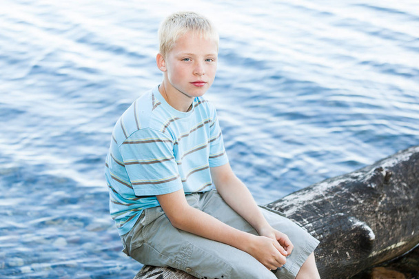 Αγόρι κάθεται σε ένα ξύλο που επιπλέει - Φωτογραφία, εικόνα