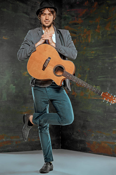 Cool guy standing with guitar on gray background - Foto, imagen
