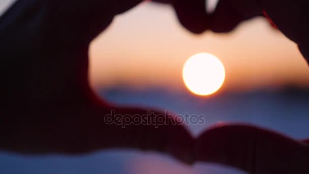 a lány így szív kézzel a nap. Sziluettjét kéz a szív alakú belsejében a naplementét. Téli - Felvétel, videó