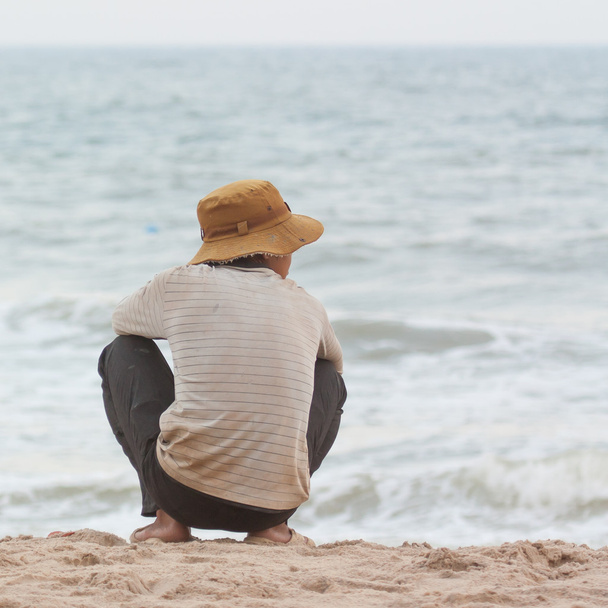 człowiek siedzi na plaży Morza południowo chińskiego - Zdjęcie, obraz