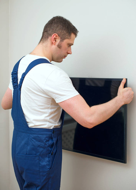 Человек монтирует телевизор на стене
. - Фото, изображение