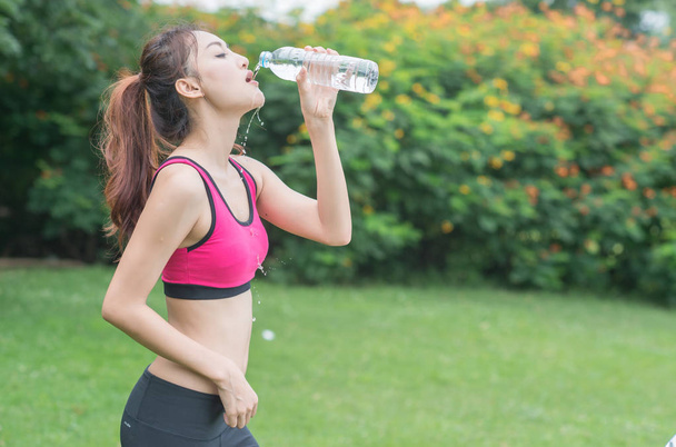 giovane donna attraente che beve acqua dalla bottiglia di plastica nel parco
 - Foto, immagini