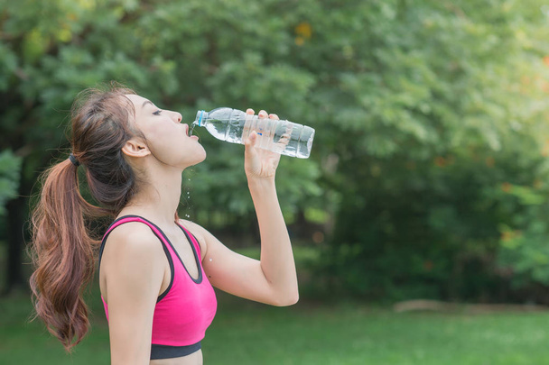 joven atractiva mujer beber agua de botella de plástico en el parque
 - Foto, Imagen