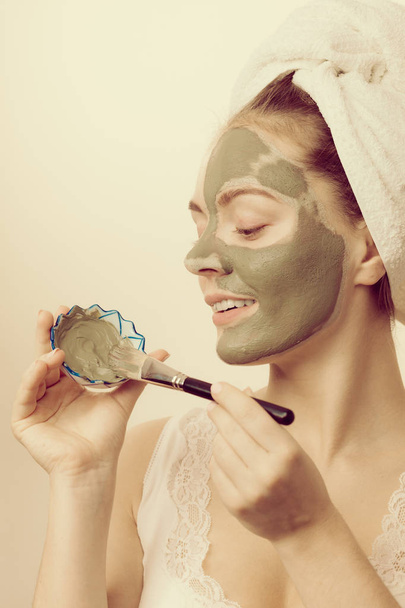 Woman applying with brush clay mud mask to her face  - Foto, Imagen