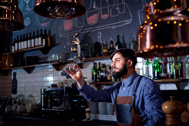 Bartender, barista work looks at clean glass in restaurant behin - Fotografie, Obrázek