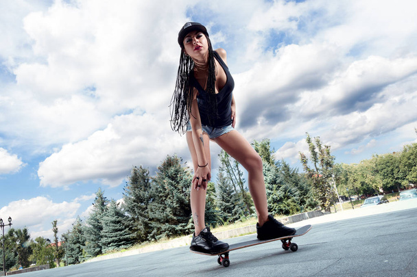 stijlvolle meisje in sexy korte broek op een skateboard - Foto, afbeelding