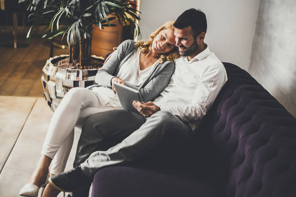 Paar sitzt auf Sofa und schaut auf Tablet - Foto, Bild