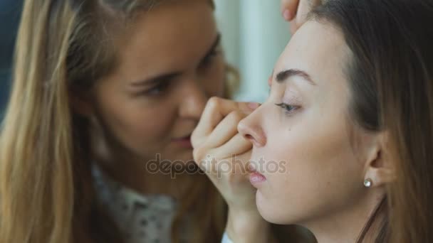 Young make-up artist makes a girl beautiful makeup for eyes closeup before an important event - Footage, Video